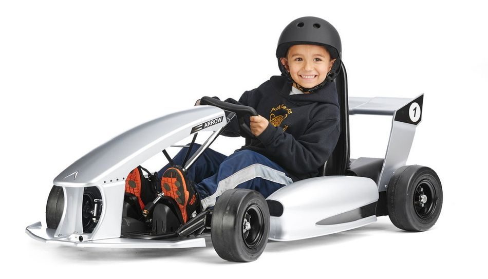 Child in a helmet driving an electric kart on a track